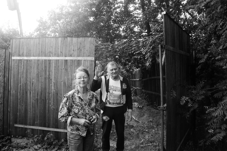 two people standing by a fence, some with straw