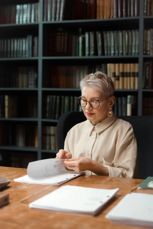 woman reading a book in front of a liry full of books