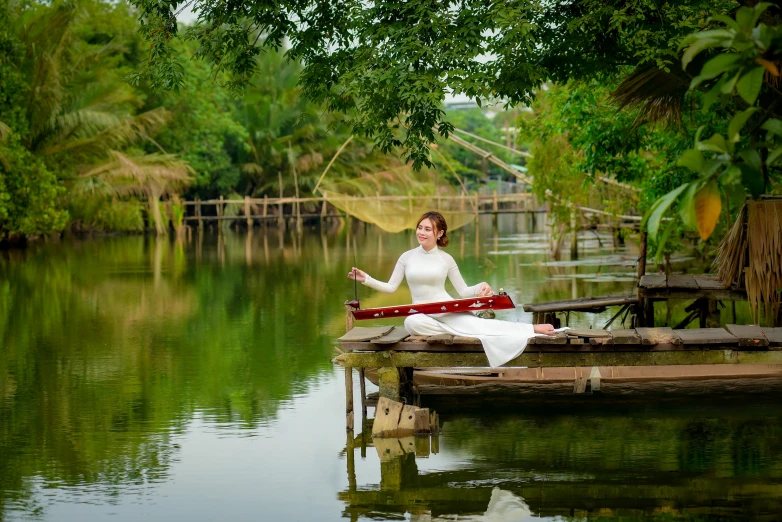 a woman sitting on the water holding a red bow