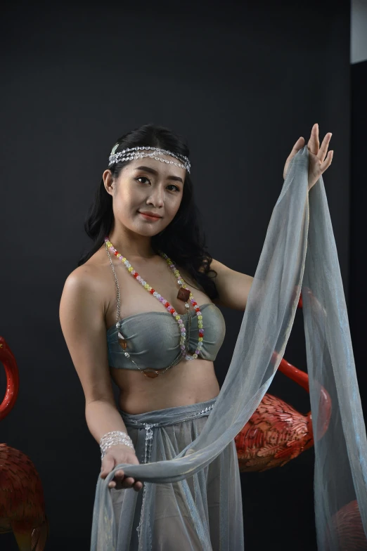 a beautiful woman in costume holding up a piece of cloth