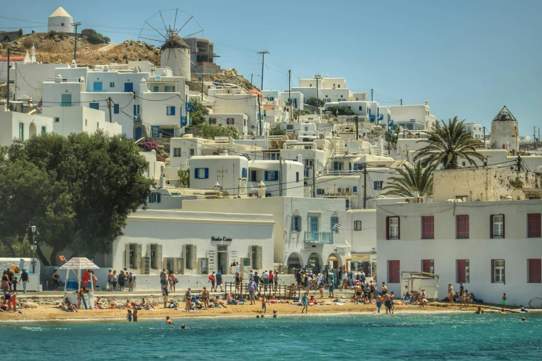 many people are sitting on the beach near a hill