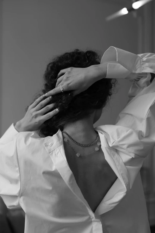 woman adjusting a white collared shirt in black and white