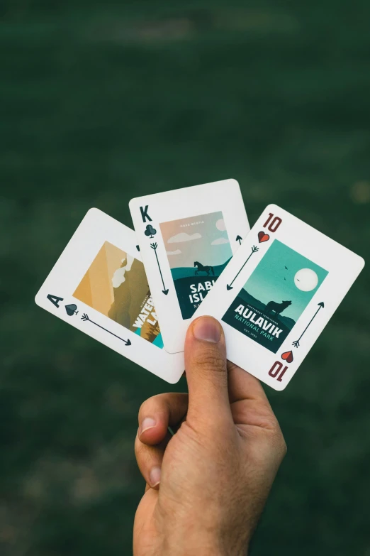 two playing cards with one playing the card and another one displaying a mountain range