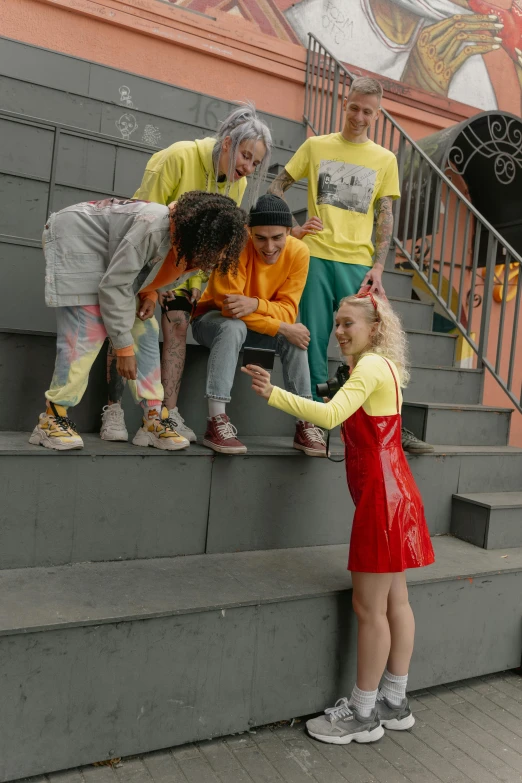 a girl in yellow stands on the steps of a staircase with others