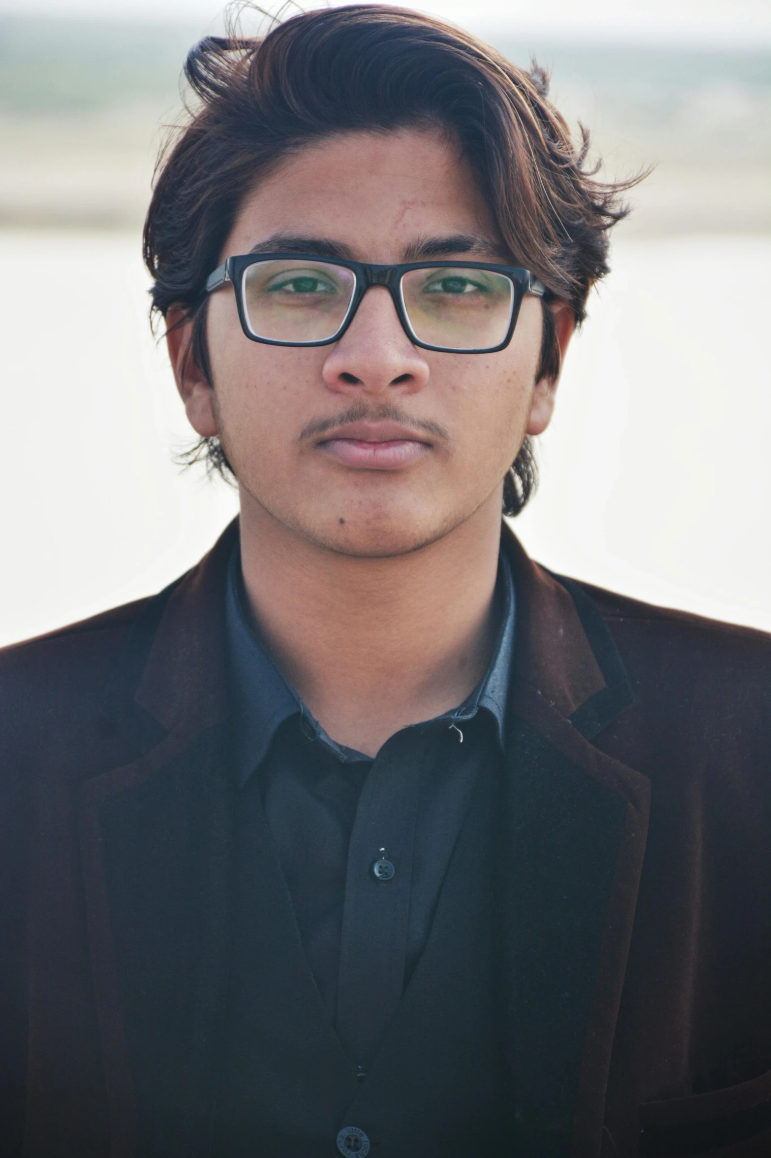 man with black jacket and eyeglasses by the water