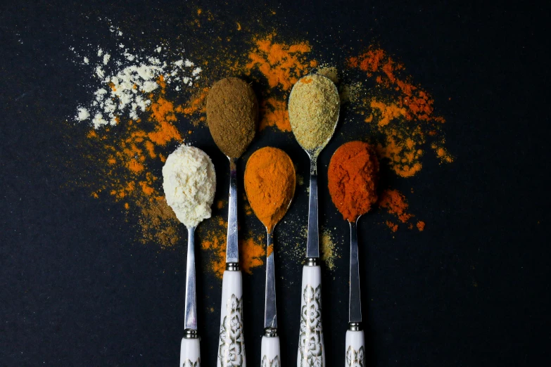 there is different colored spices in the spoons