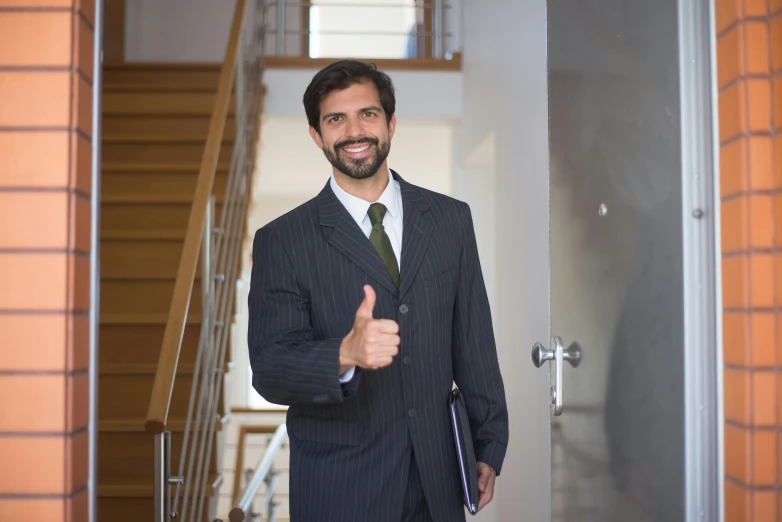 a man dressed in business attire giving the thumbs up