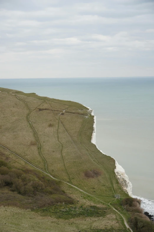 a grassy hill near the beach on a cloudy day