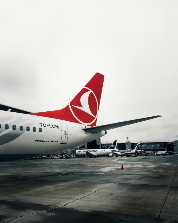 a red and white plane sits parked on the runway