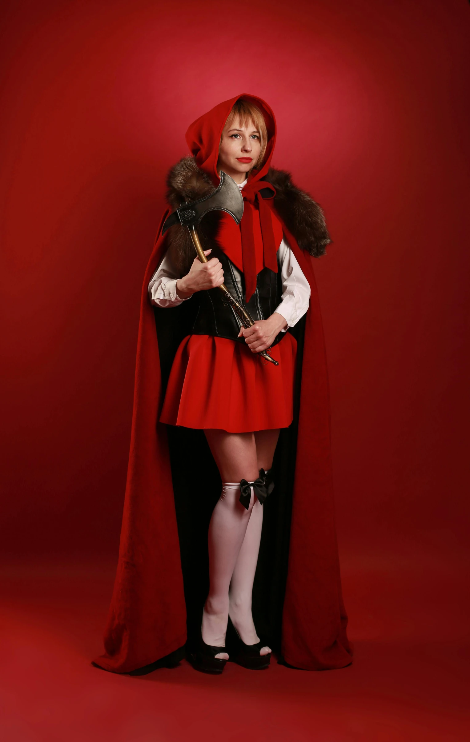 a lady dressed in a medieval style red outfit and fur hat, standing on a red background