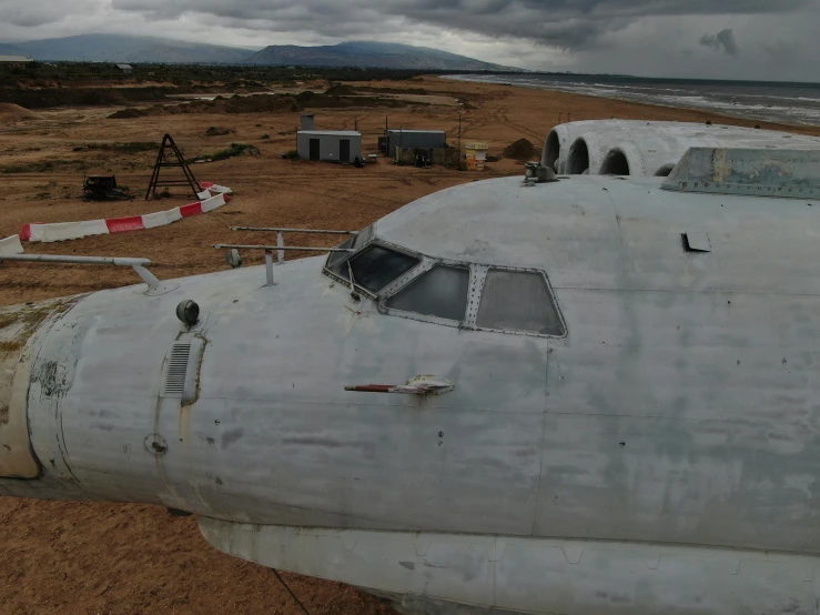 the nose of an old white airplane at an abandoned airport