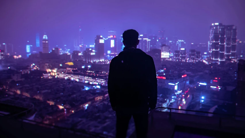 man overlooking the city at night in a very high way