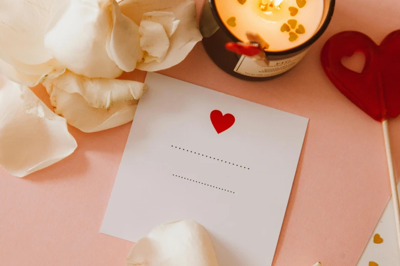 paper, white roses and candle on a pink surface