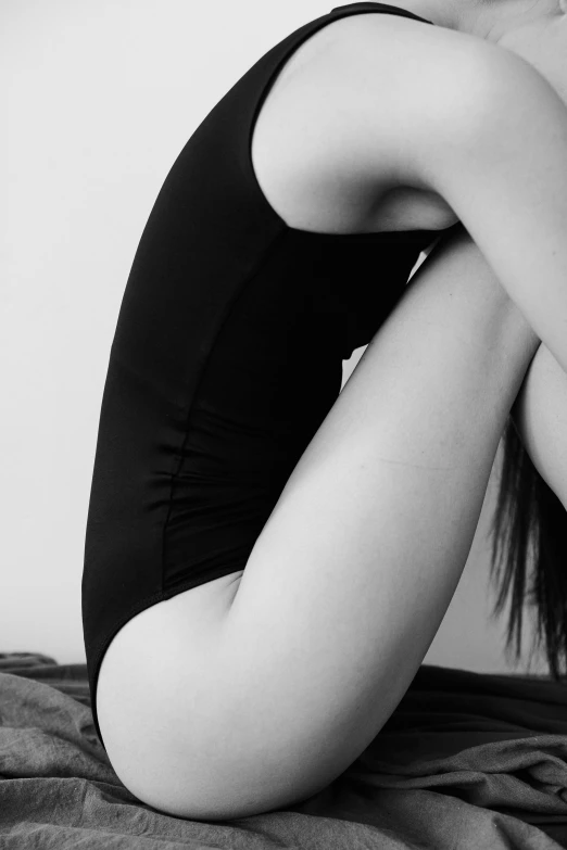 a woman in lingerie sits with her back against a wall