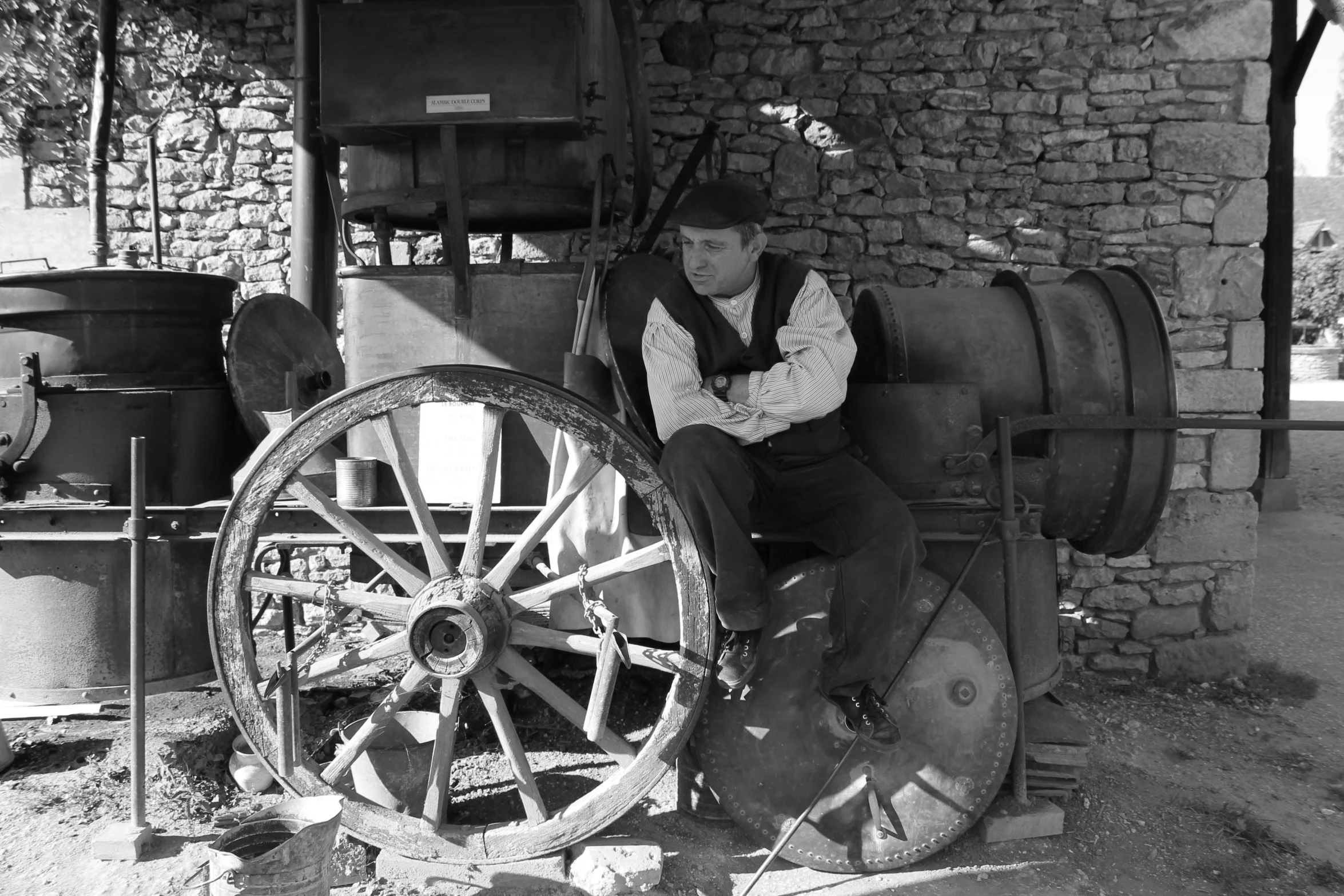 a person sits on a wooden wheel by a stone building