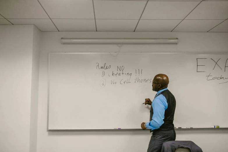 two men sit at a white board in an office