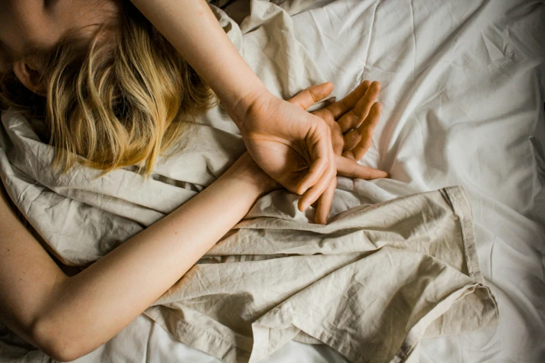 a  woman laying in bed next to a white sheet