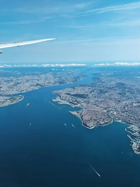 an airplane wing with a city view of a river and bridge in the background