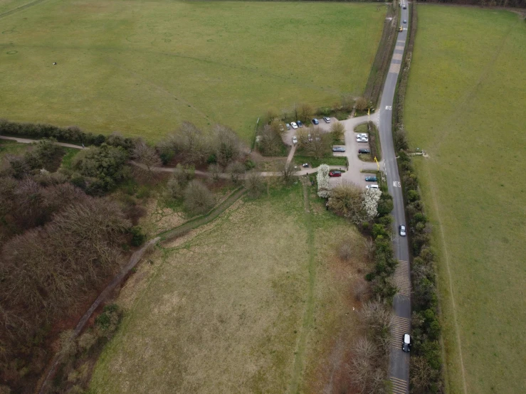 an aerial view of a road surrounded by green fields