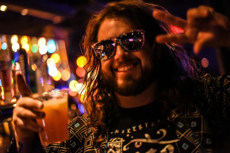 a man holding a drink in front of a bar