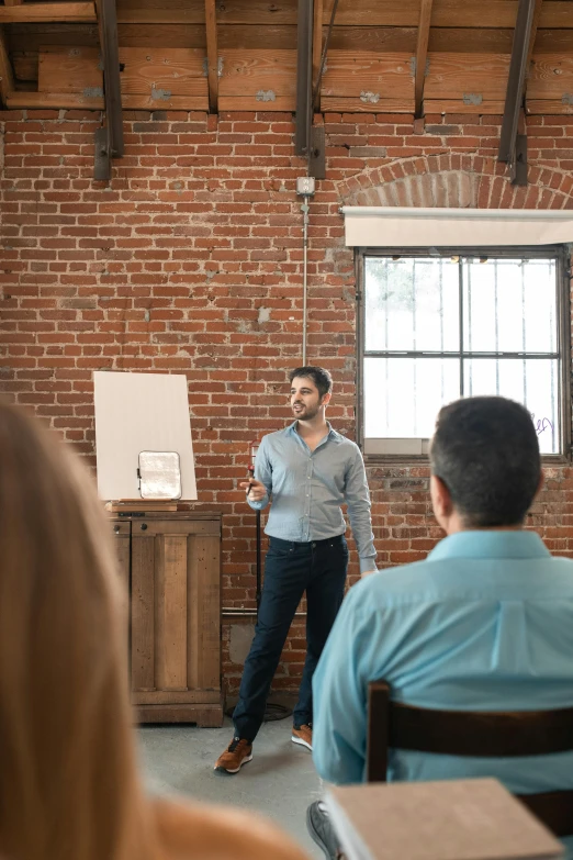 a man in a blue shirt and tie standing in front of a class