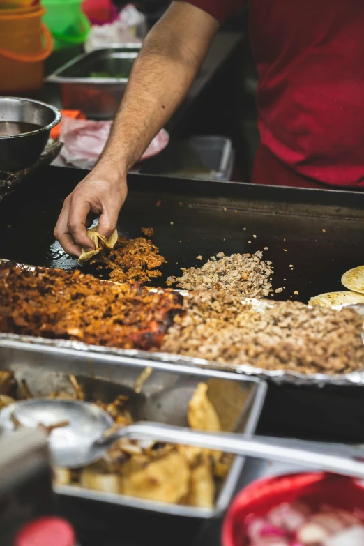 a person scoops food from a tray in the middle of a table