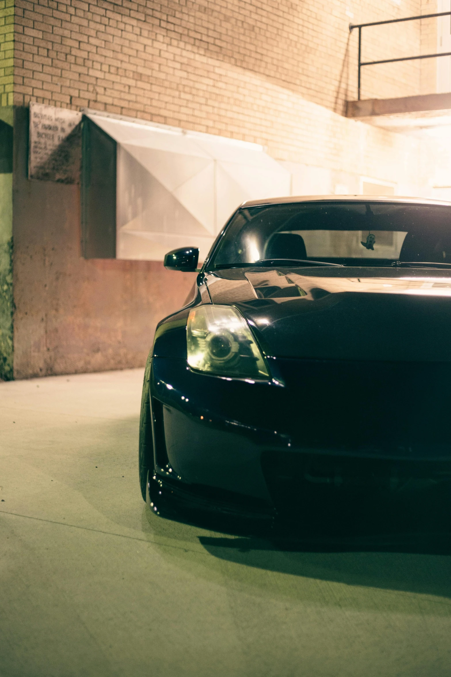 the back end of a black car parked on a concrete ground