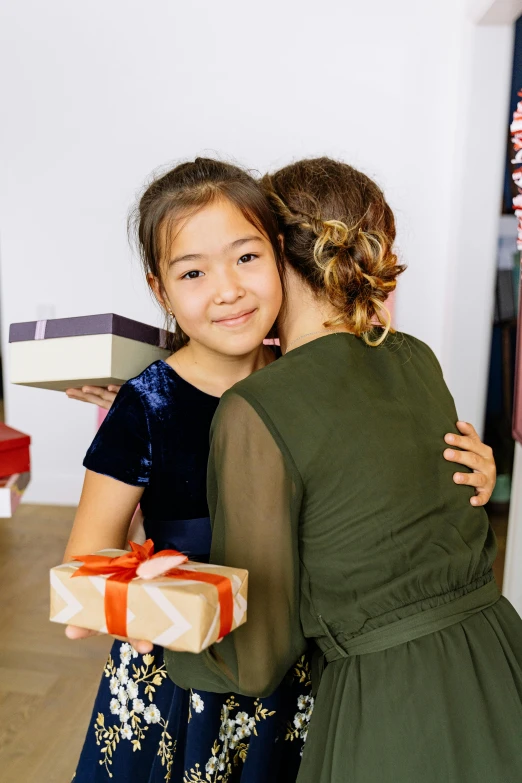 a woman is holding her daughter wrapped presents