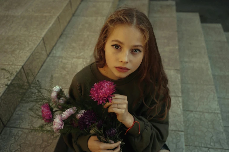 a girl is holding flowers in her hands