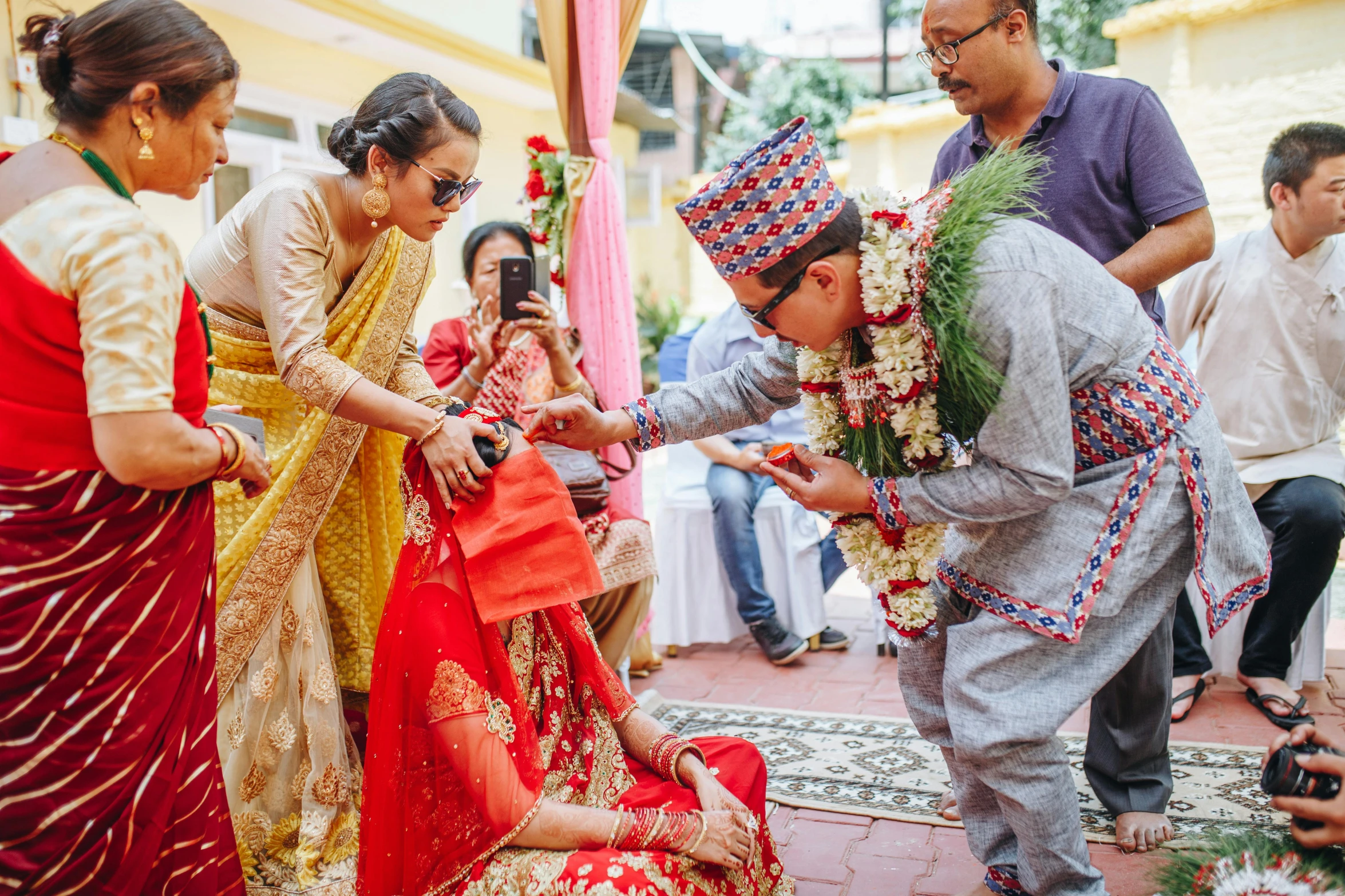 a man kneeling down to touch the hands of two women