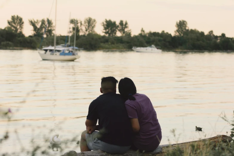 two people sitting next to each other on top of a rock