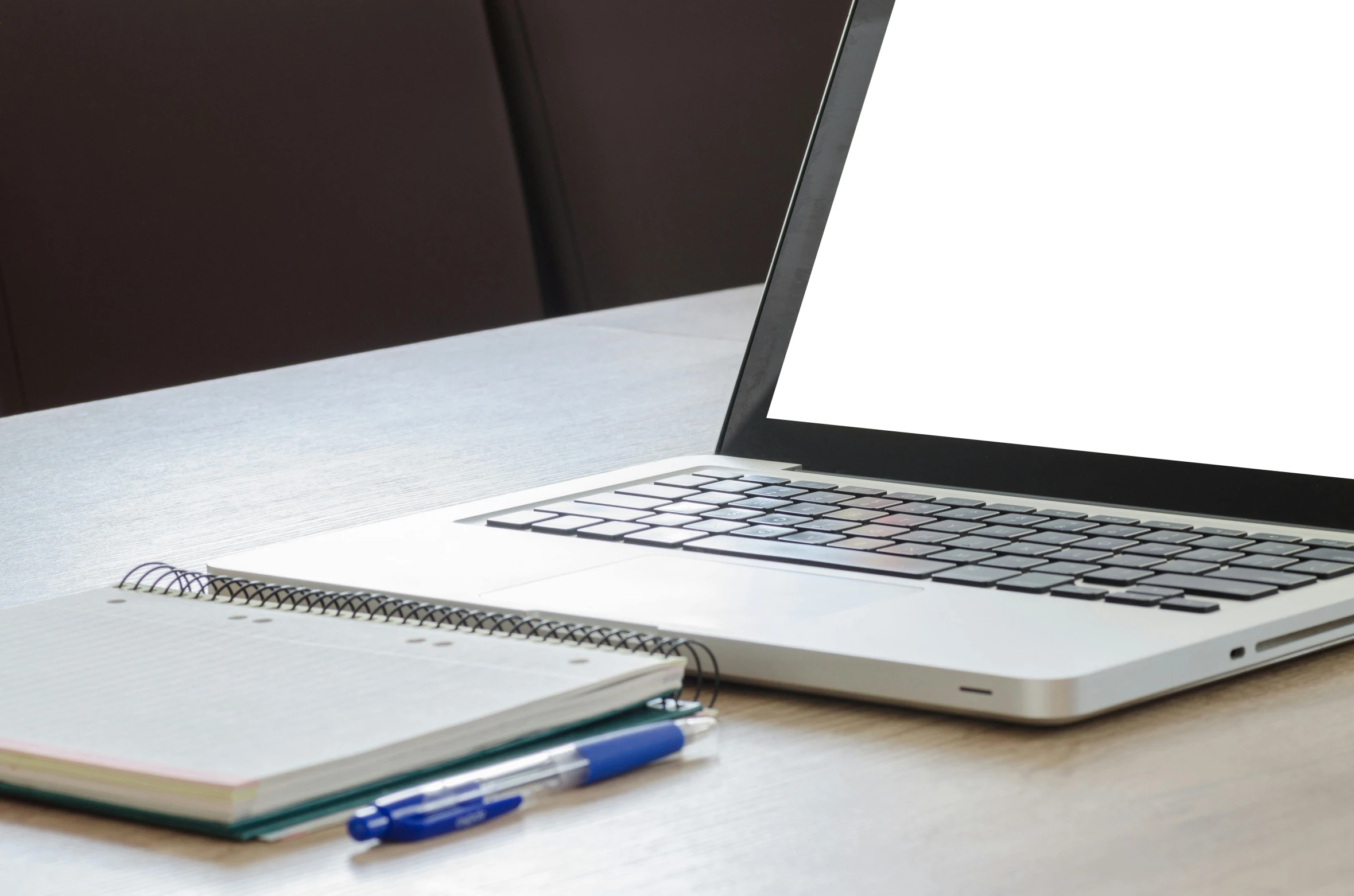 an open notebook sits beside a laptop computer