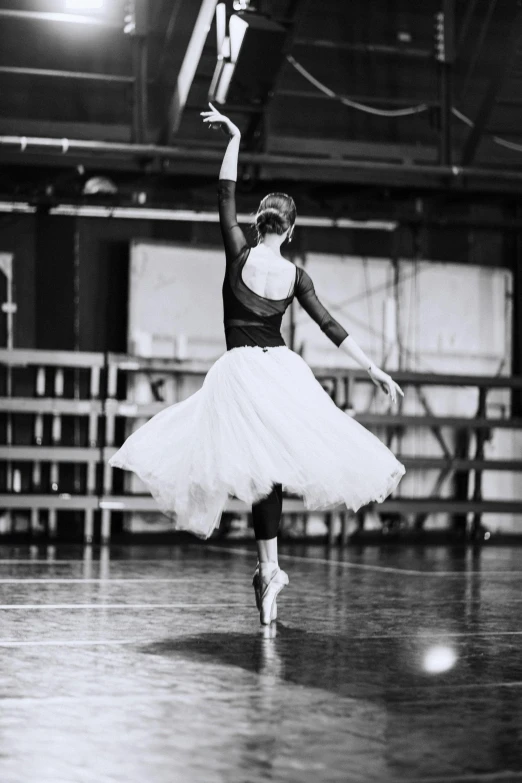 a woman in a skirt and sneakers in an empty dance hall