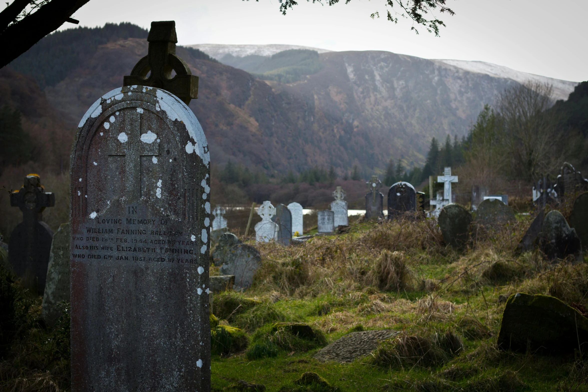 a bunch of graves sitting near a cemetery on the side of a hill