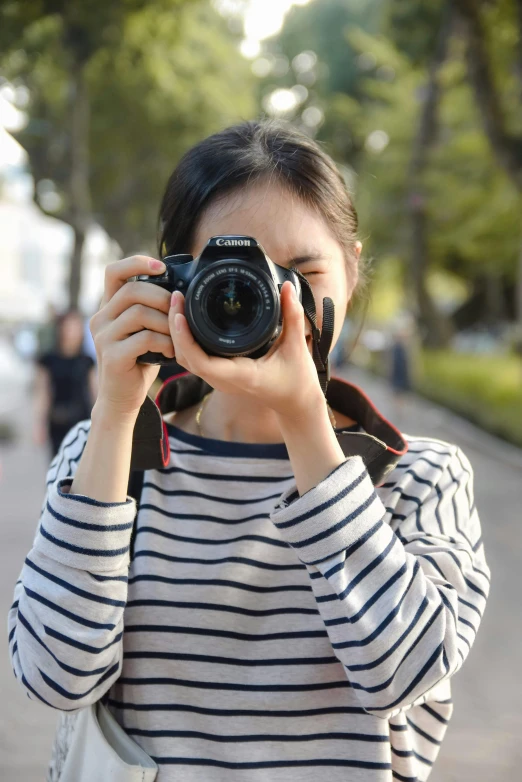 a woman takes a po with her camera in front of a park