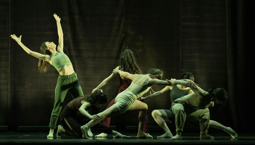 a woman is stretching on stage in an artistic fashion