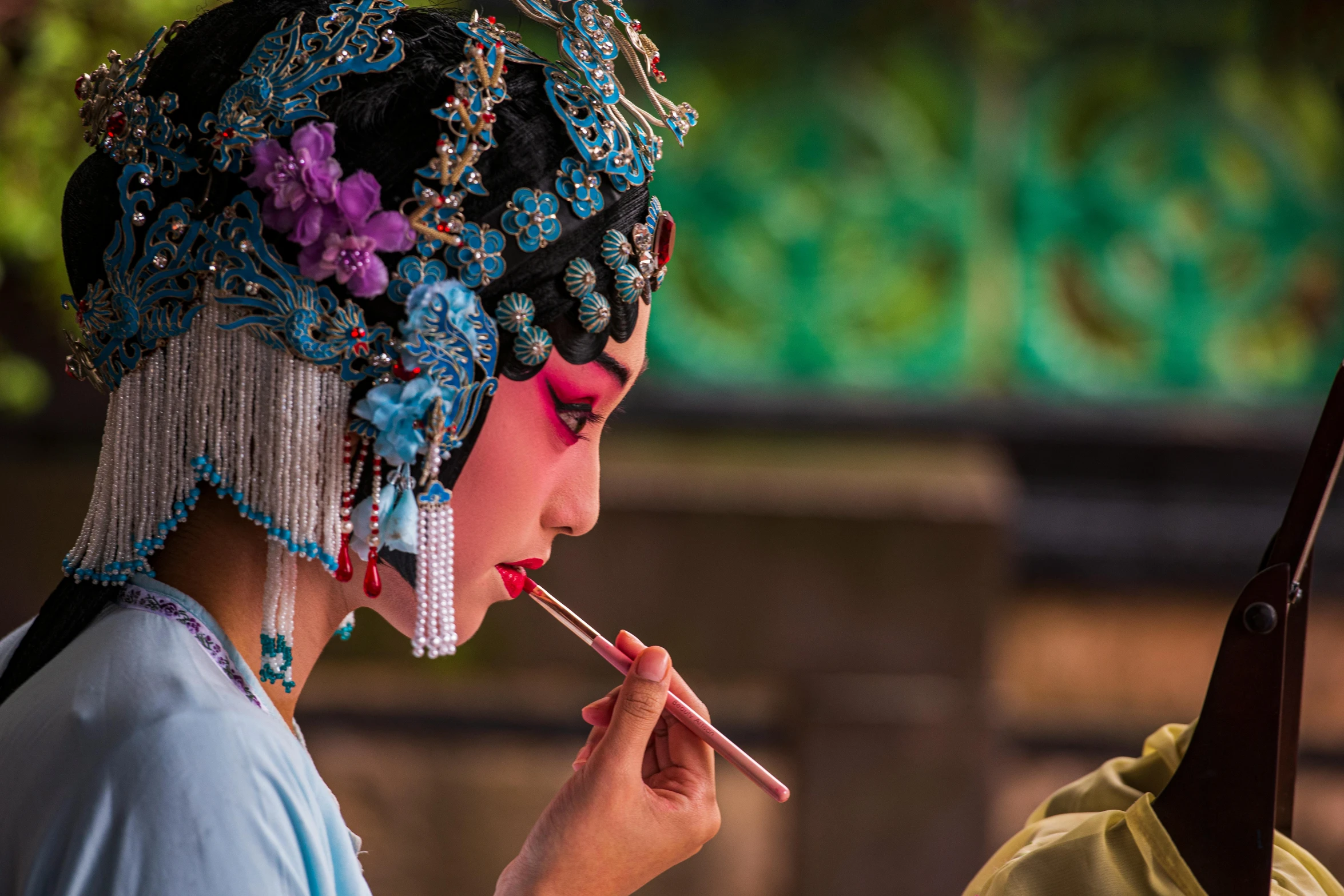 woman in oriental garb holds a pencil to her lips