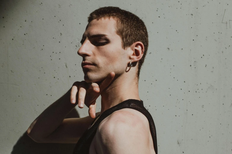 a man standing and wearing black clothes has his hand in his ear