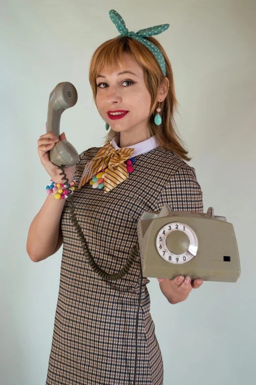 a woman in a dress and bow hat holding an old fashioned phone