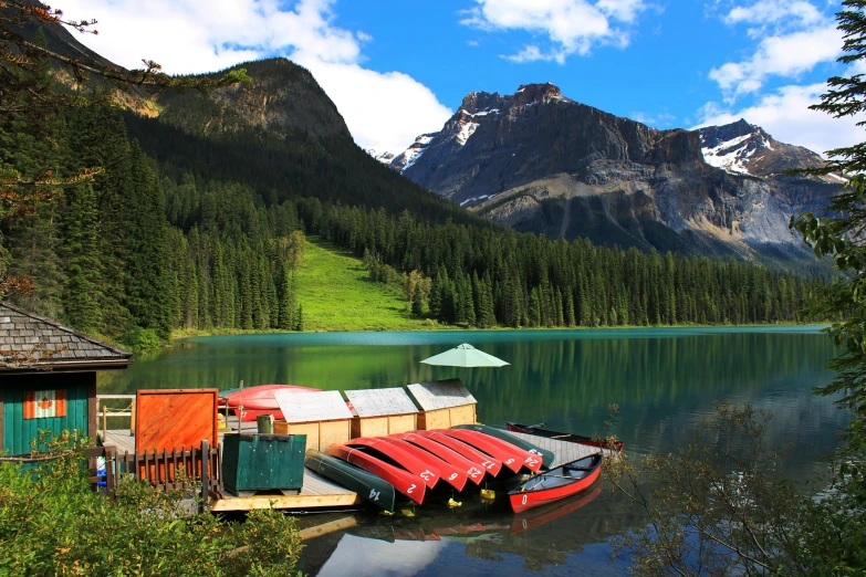 a red and white boat in the water with a mountain and trees behind it