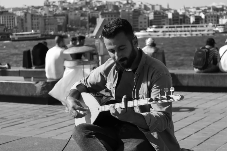 a man sitting on a pier playing an acoustic guitar