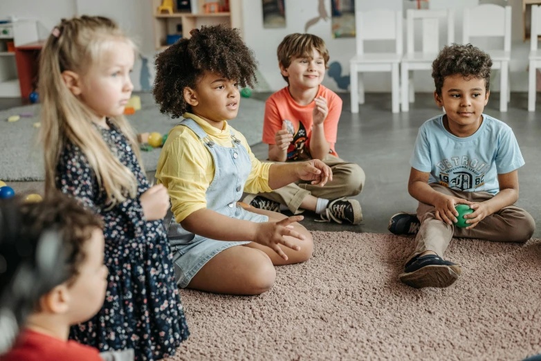 group of children sitting on the floor and talking to each other