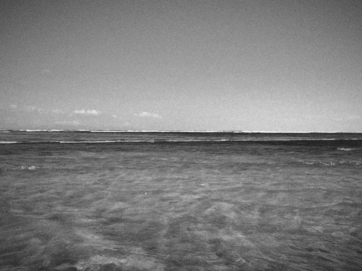 black and white pograph of a lonely boat sitting at the end of the ocean