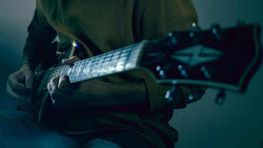 a man is playing his guitar in the dark