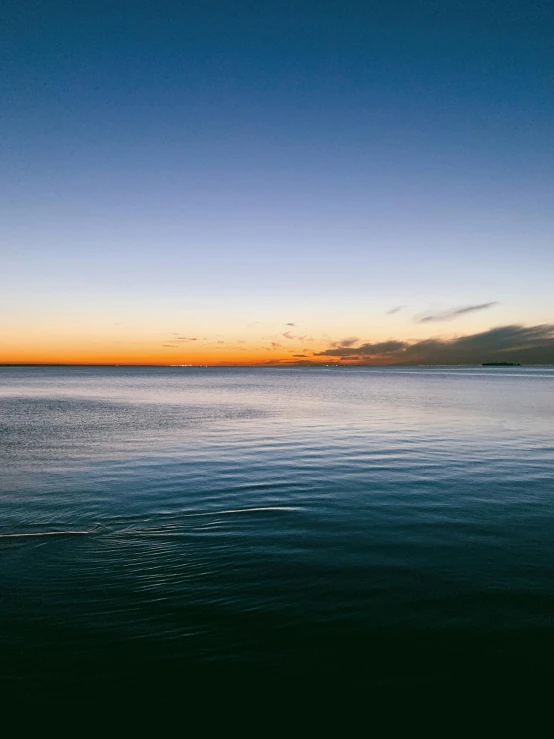 a calm ocean with a setting sun in the background