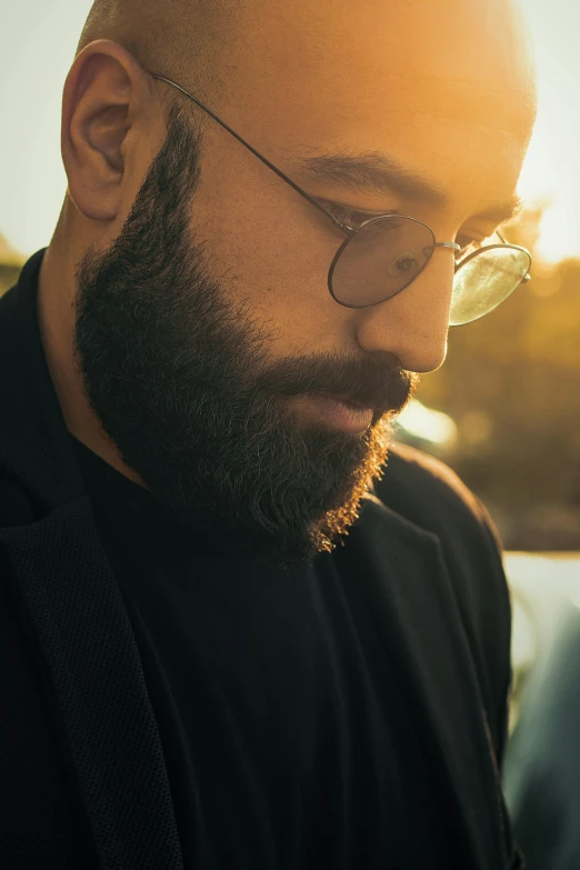 a bald man wearing black and a pair of glasses