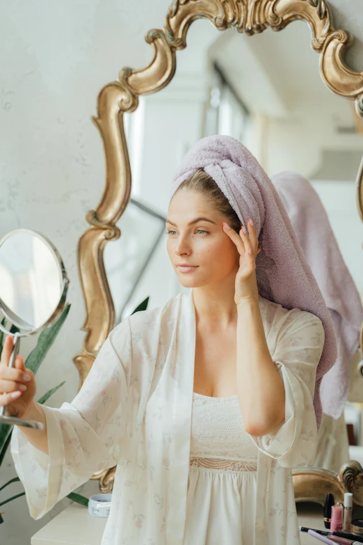 a woman standing in front of a mirror while touching her head