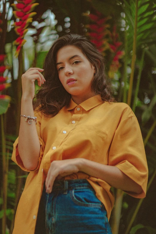 the girl is posing for the camera wearing a yellow shirt and jeans