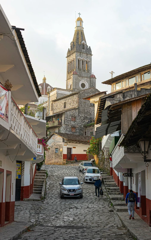 a person walking up a street with cars parked on both sides