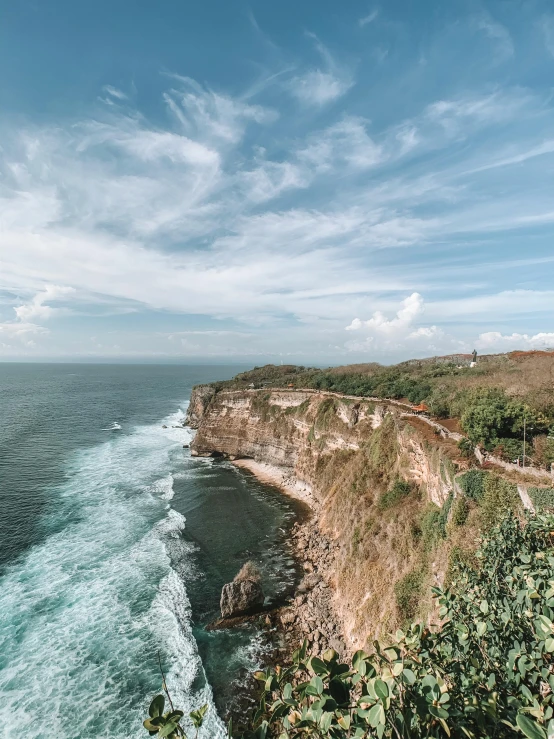 the ocean is next to a cliff, and there is a beach